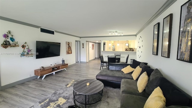 living room featuring baseboards, ornamental molding, visible vents, and wood finished floors