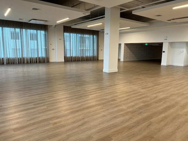 empty room with wood finished floors, visible vents, and baseboards