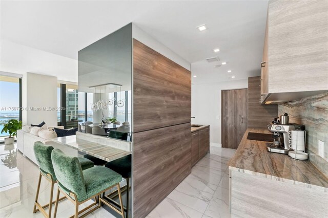 650 NE 32nd St Unit Ph5004, Miami, FL 33137 - kitchen featuring light marble finish flooring, modern cabinets, recessed lighting, and a wood stove