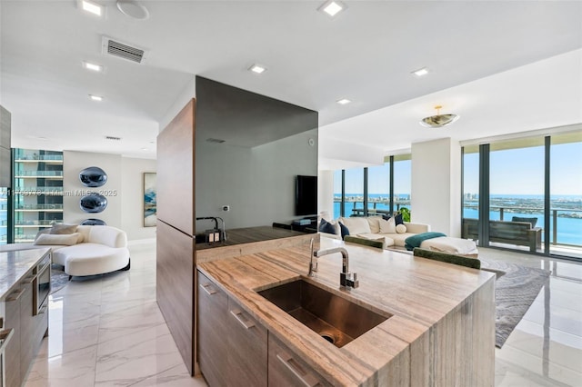 650 NE 32nd St Unit Ph5004, Miami, FL 33137 - kitchen with open floor plan, modern cabinets, a sink, light marble finish flooring, and light stone counters