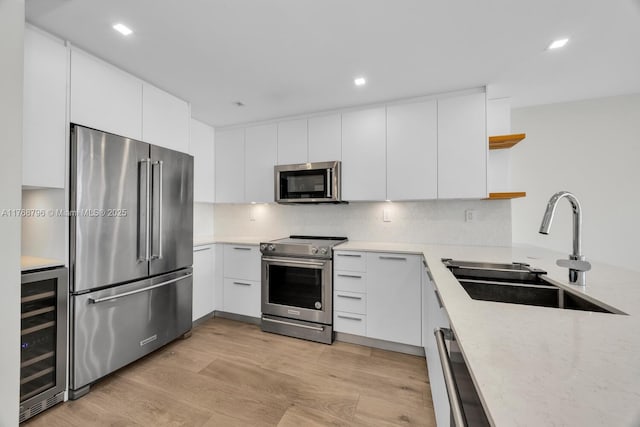 1901 Brickell Ave Unit B2304, Miami, FL 33129 - kitchen with appliances with stainless steel finishes, beverage cooler, open shelves, light wood-style floors, and white cabinets