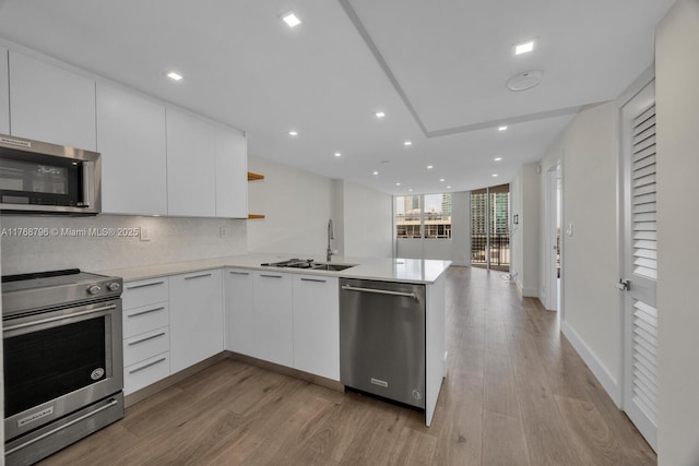 1901 Brickell Ave Unit B2304, Miami, FL 33129 - kitchen with appliances with stainless steel finishes, a peninsula, modern cabinets, light wood-style flooring, and recessed lighting