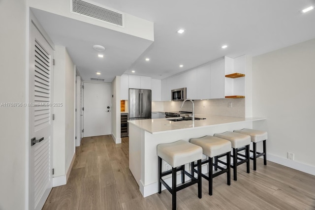 1901 Brickell Ave Unit B2304, Miami, FL 33129 - kitchen with open shelves, a peninsula, appliances with stainless steel finishes, a breakfast bar area, and modern cabinets