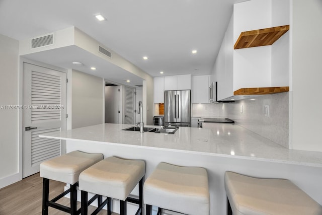 1901 Brickell Ave Unit B2304, Miami, FL 33129 - kitchen with appliances with stainless steel finishes, a peninsula, decorative backsplash, light wood finished floors, and white cabinets
