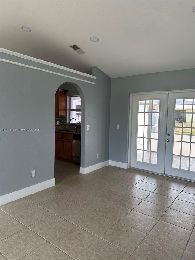 1715 NE 2nd Ave, Cape Coral, FL 33909 - spare room featuring baseboards, a sink, arched walkways, and french doors