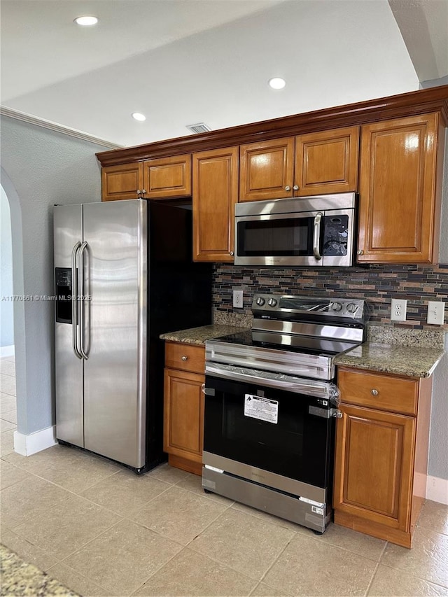 1715 NE 2nd Ave, Cape Coral, FL 33909 - kitchen featuring stainless steel appliances, arched walkways, tasteful backsplash, brown cabinetry, and recessed lighting