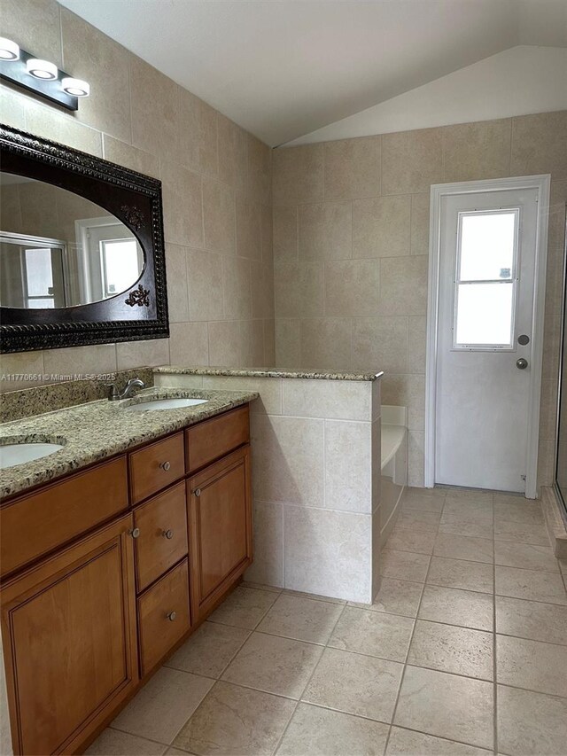 1715 NE 2nd Ave, Cape Coral, FL 33909 - full bath with tile walls, vaulted ceiling, double vanity, a bath, and a shower stall