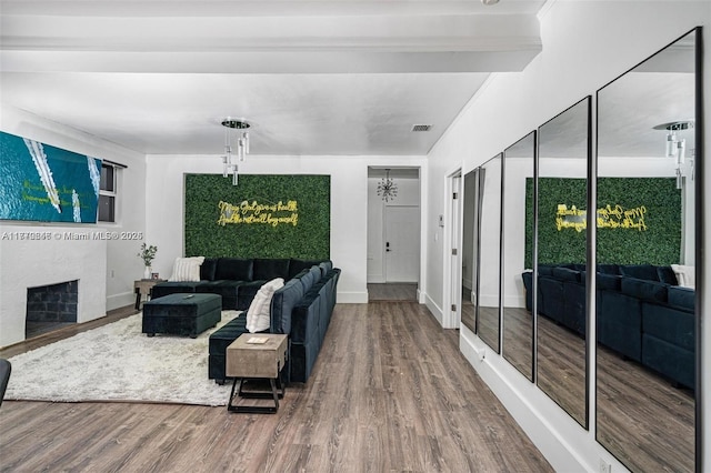 living room featuring visible vents, baseboards, a fireplace, and wood finished floors