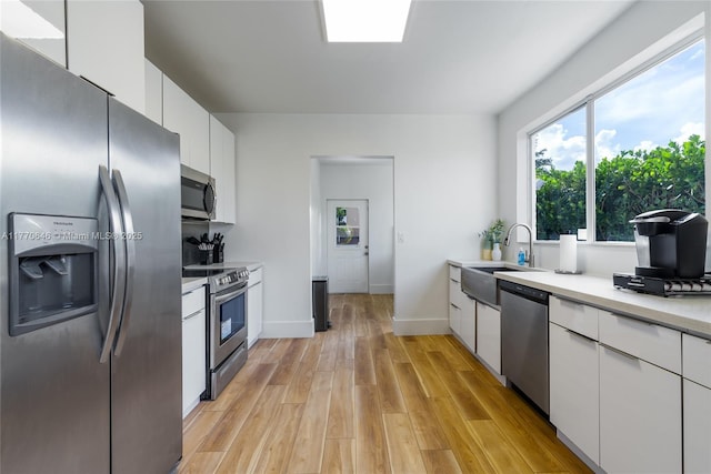 1114 SW 11th Ave, Miami, FL 33129 - kitchen featuring appliances with stainless steel finishes, white cabinetry, light countertops, light wood finished floors, and modern cabinets