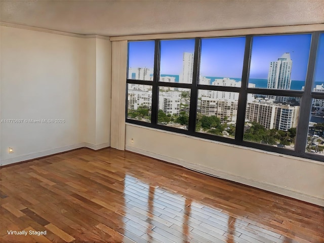 spare room with hardwood / wood-style floors, baseboards, and a city view