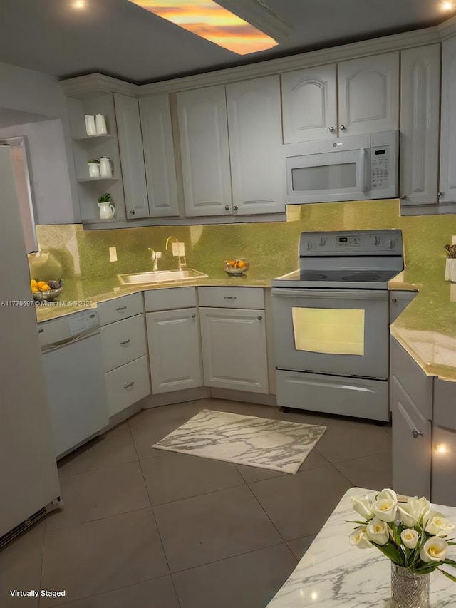kitchen with decorative backsplash, light tile patterned flooring, white cabinets, white appliances, and a sink