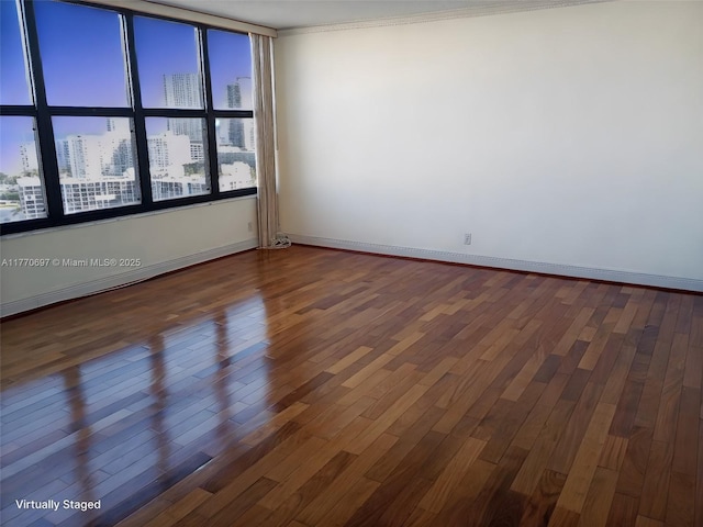 spare room featuring baseboards, a view of city, and wood finished floors