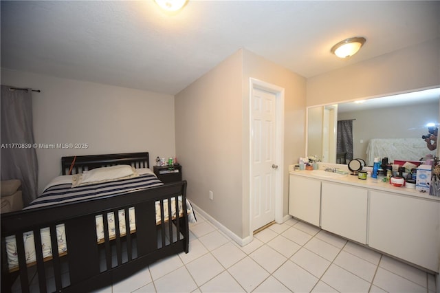 bedroom featuring light tile patterned flooring, baseboards, and a sink