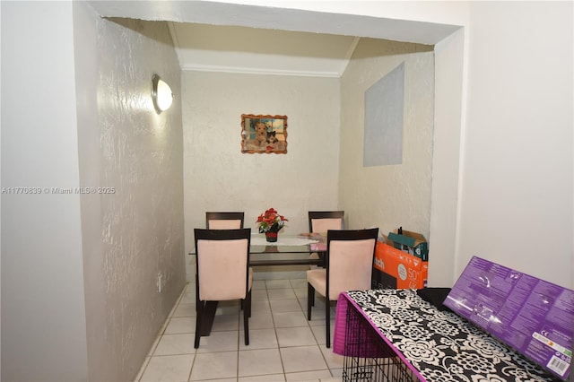 tiled dining space with crown molding and a textured wall