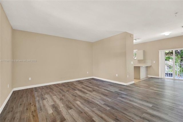 unfurnished living room featuring baseboards and wood finished floors