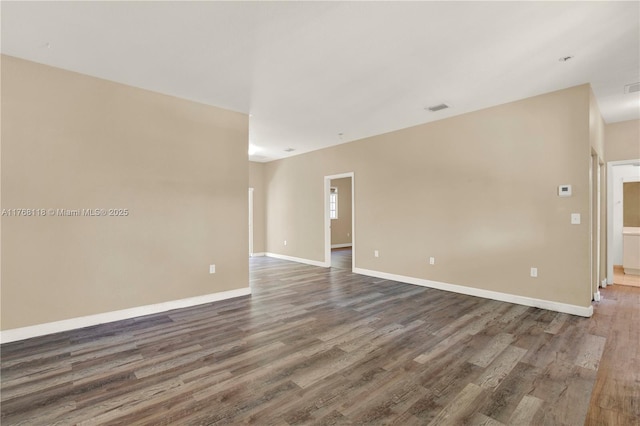 spare room featuring baseboards, visible vents, and wood finished floors