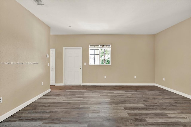 empty room featuring visible vents, baseboards, and wood finished floors
