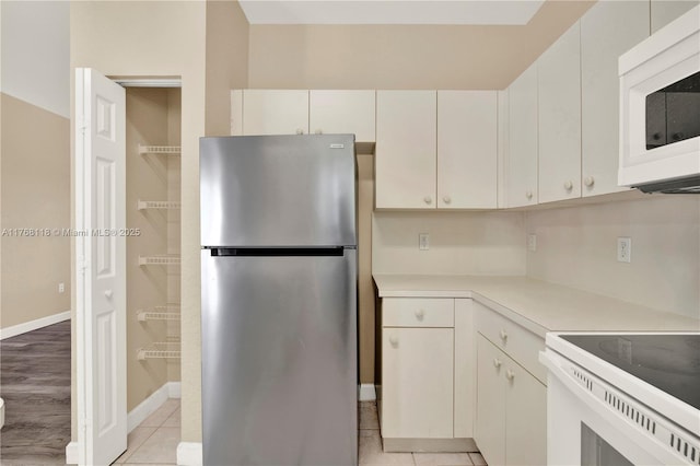 kitchen featuring white cabinetry, light countertops, light tile patterned flooring, and white appliances