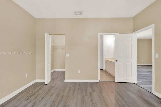 unfurnished bedroom with light wood-style flooring, a closet, baseboards, and visible vents