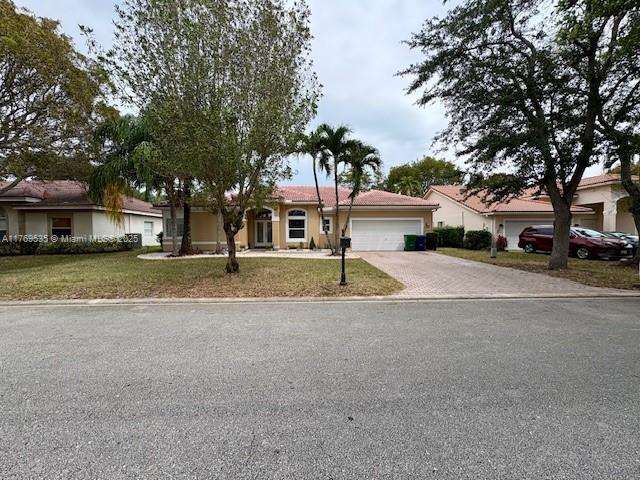 ranch-style home with a front lawn, driveway, stucco siding, and a garage