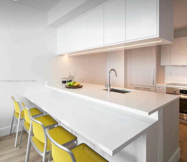 kitchen featuring modern cabinets, a sink, a peninsula, and oven