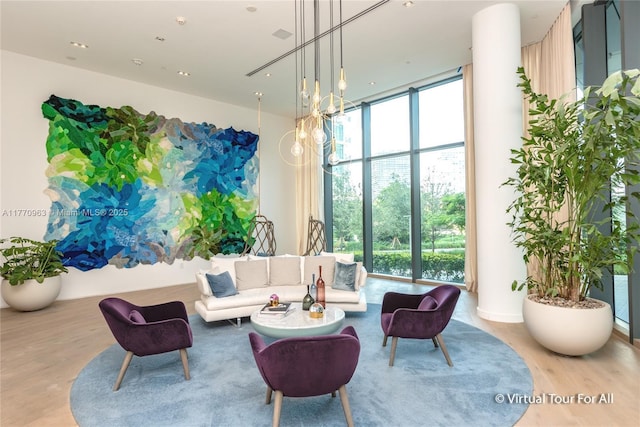 living area featuring a wealth of natural light, floor to ceiling windows, and wood finished floors