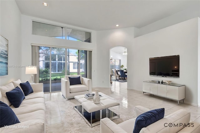 living room with arched walkways, recessed lighting, light tile patterned floors, and a towering ceiling