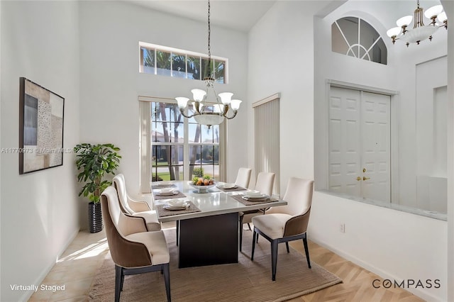 dining room featuring an inviting chandelier, baseboards, and a high ceiling