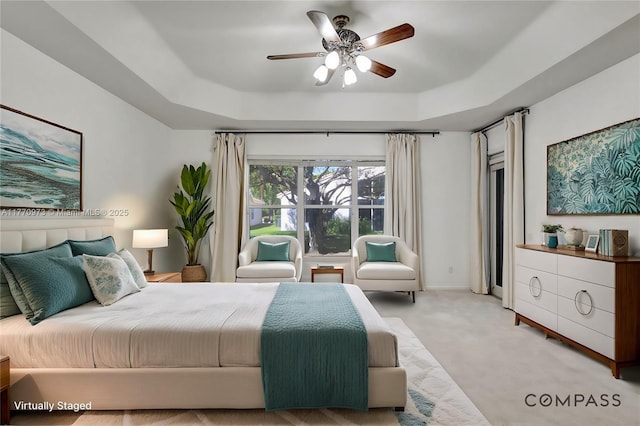 bedroom featuring a raised ceiling, a ceiling fan, and light colored carpet