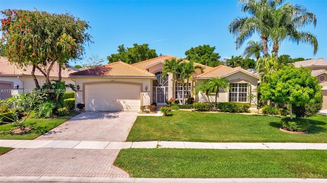 mediterranean / spanish home featuring a front yard, decorative driveway, stucco siding, a tiled roof, and an attached garage