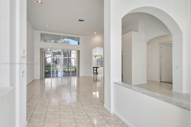 hall with light tile patterned flooring, an inviting chandelier, arched walkways, recessed lighting, and visible vents