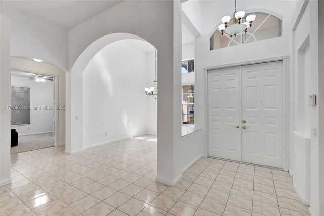 foyer featuring arched walkways, ceiling fan with notable chandelier, and light tile patterned flooring