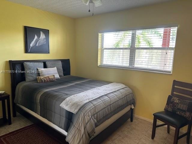 tiled bedroom featuring baseboards, multiple windows, and a textured ceiling