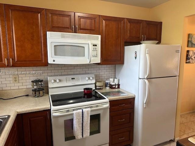 kitchen featuring light countertops, a sink, brown cabinets, white appliances, and decorative backsplash