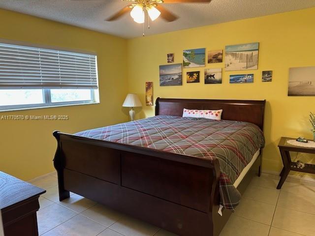 bedroom featuring light tile patterned flooring, a textured ceiling, and ceiling fan