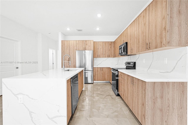 kitchen with modern cabinets, a sink, an island with sink, and appliances with stainless steel finishes