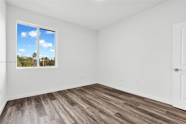 spare room featuring dark wood-style flooring and baseboards