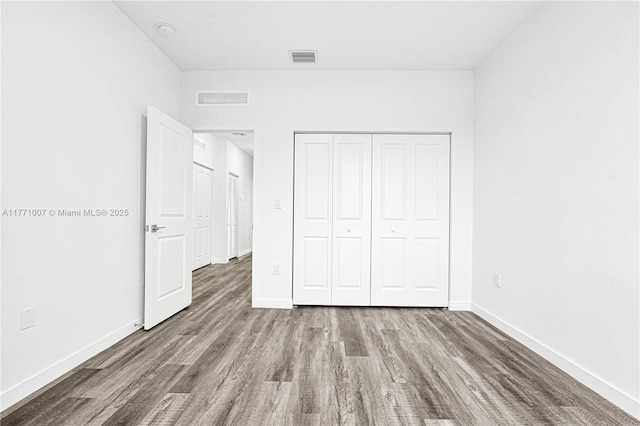 unfurnished bedroom with baseboards, visible vents, and wood finished floors