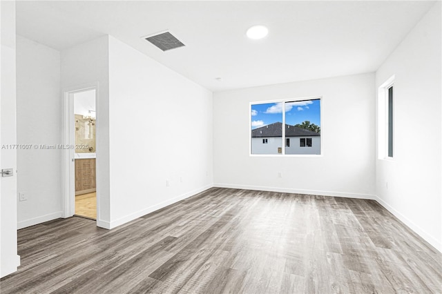 unfurnished room with wood finished floors, baseboards, and visible vents