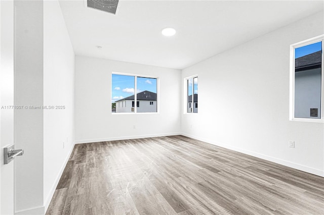 spare room with baseboards, visible vents, and wood finished floors