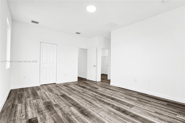 unfurnished bedroom with baseboards, visible vents, a closet, and dark wood finished floors