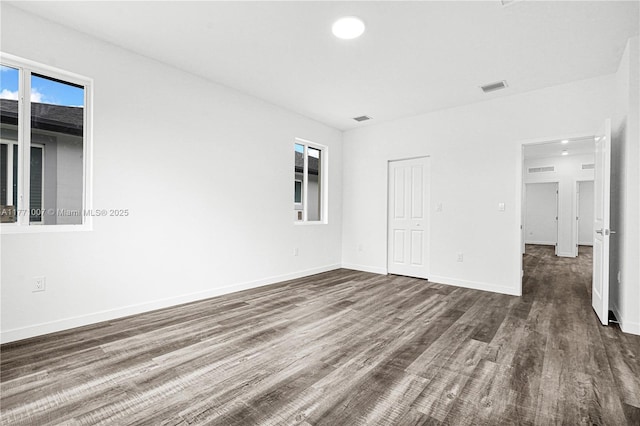 unfurnished bedroom featuring dark wood-style floors, baseboards, and visible vents