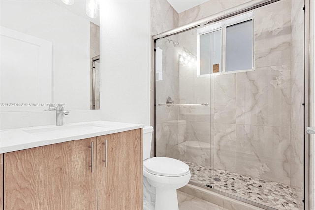 bathroom featuring marble finish floor, toilet, vanity, and a shower stall