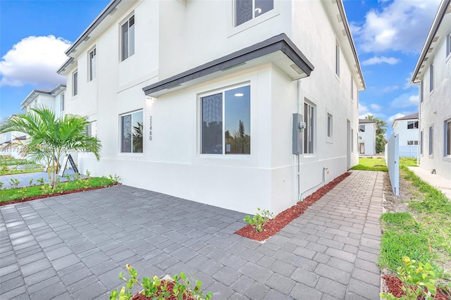 view of side of property with stucco siding and a patio
