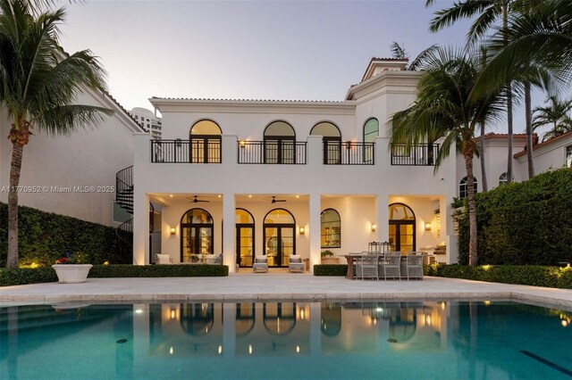 3918 Island Estates Dr, Aventura, FL 33160 - back of house at dusk with a patio, a balcony, french doors, and an outdoor pool
