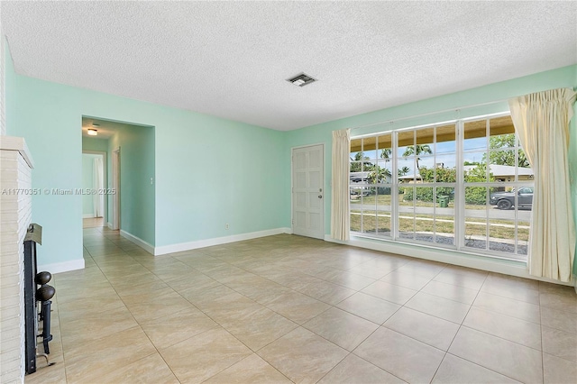 unfurnished room featuring light tile patterned floors, a textured ceiling, baseboards, and visible vents