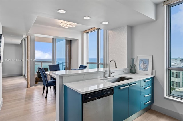 kitchen featuring light countertops, a sink, blue cabinetry, and dishwasher