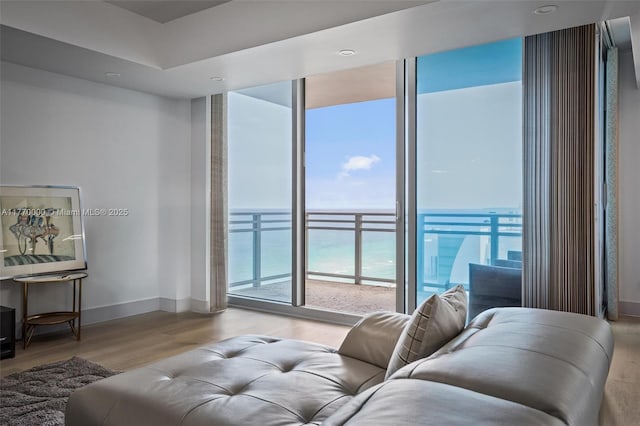 living room with baseboards, a water view, and wood finished floors