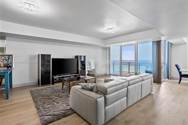 living room with baseboards, floor to ceiling windows, and light wood-type flooring