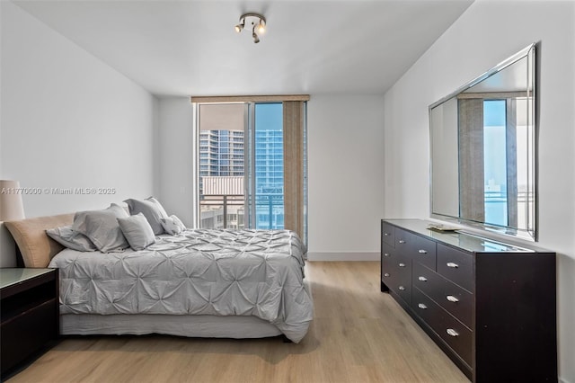 bedroom with light wood finished floors, baseboards, and access to outside